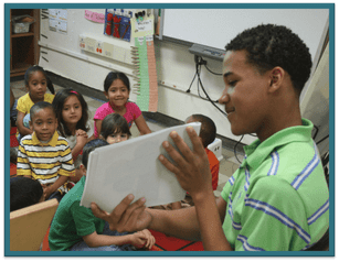 Older student reading to younger students