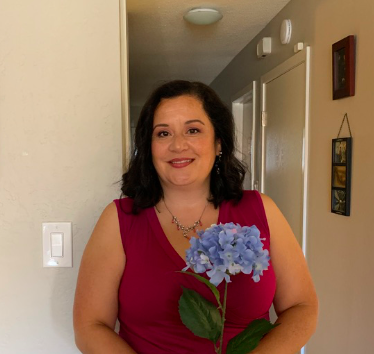 a woman presenting wearing a red dress and a light blue flower.