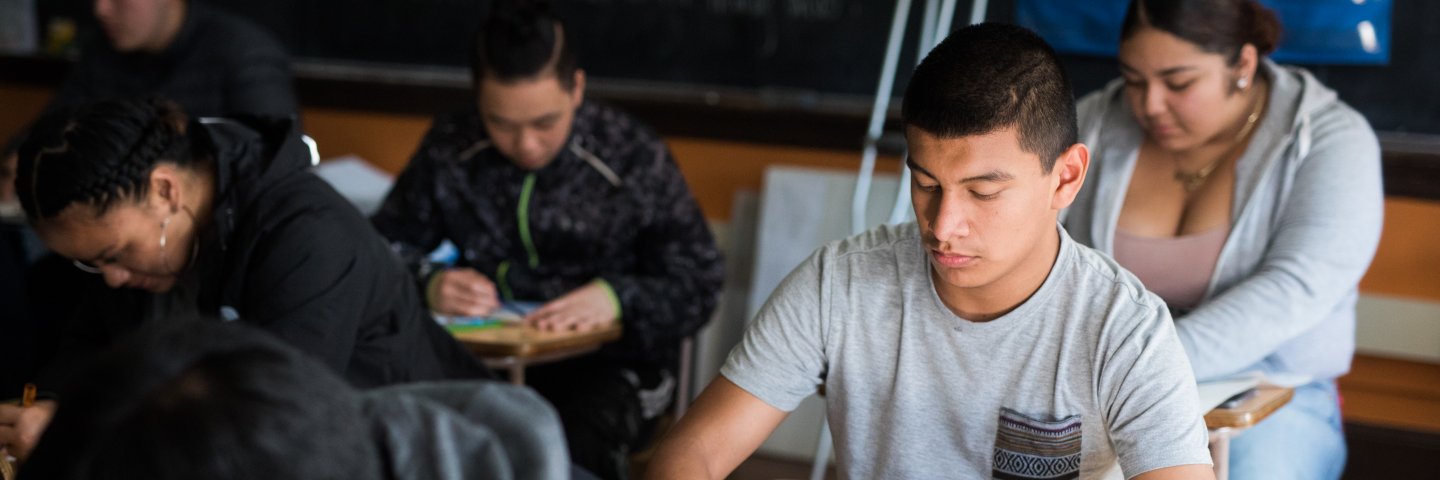 High school student sitting at desk looking at book