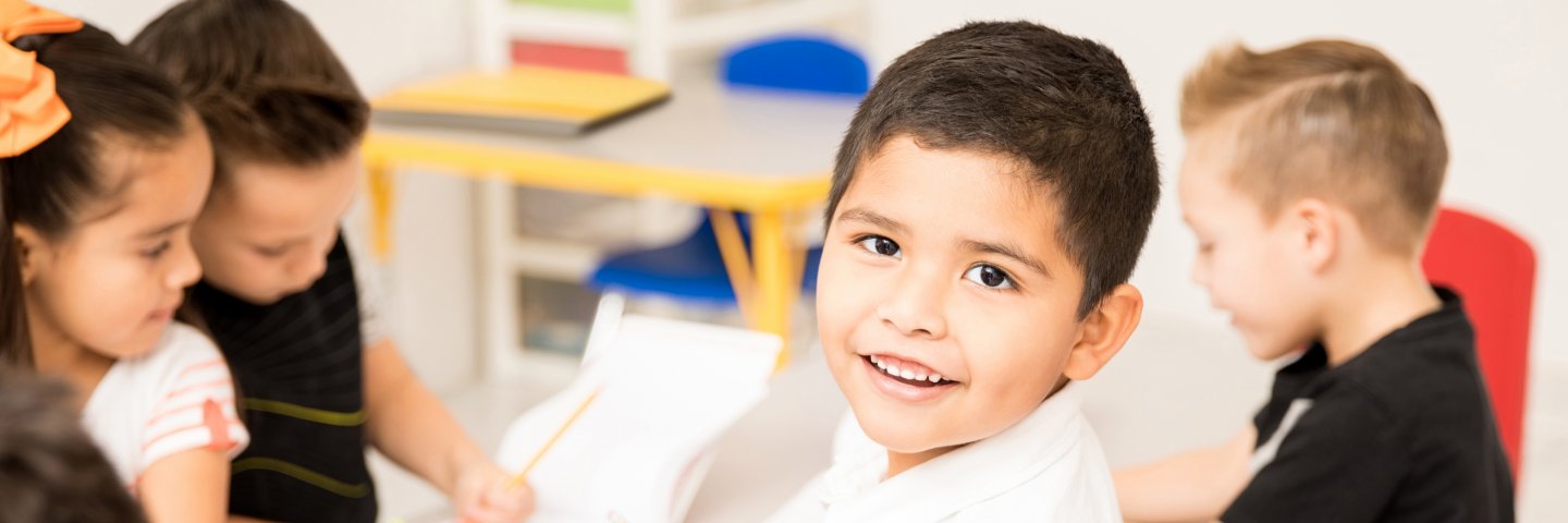 Boy holding pencil and smiling at camera