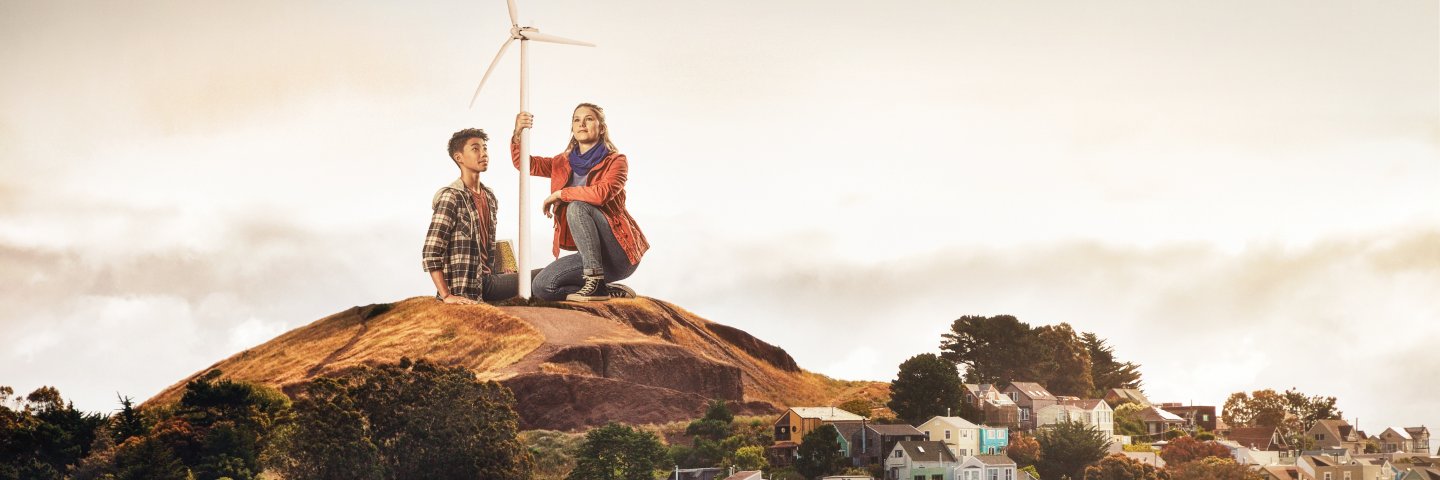 Two students by a wind turbine overlooking San Francisco