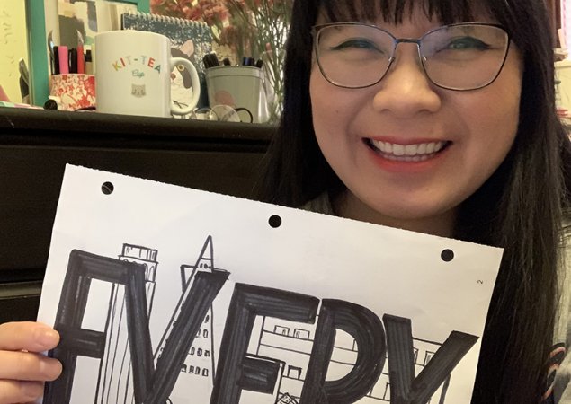 A teacher holds a sign that says "Every"