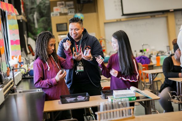Teacher with two high school students and chemistry equipment
