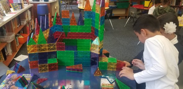 Students collaborating on a large magnatile structure.