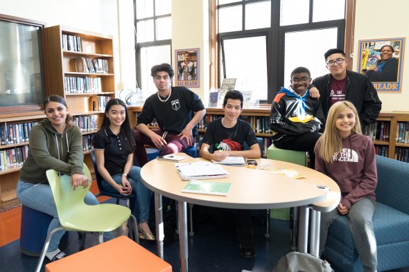 Students sit around a table. 