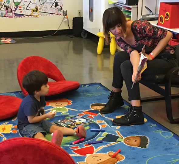 young boy being read to by high school student