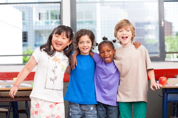 Four students with arms around each other standing shoulder to shoulder smiling