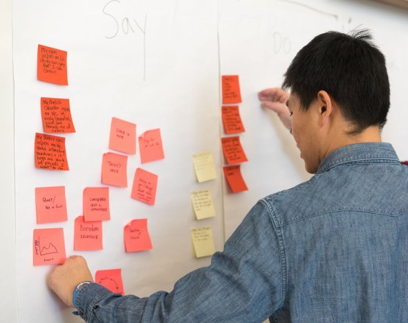  person placing post-its on a white board