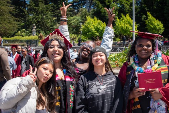 photo of two smiling graduates, two IHS students, and one family member