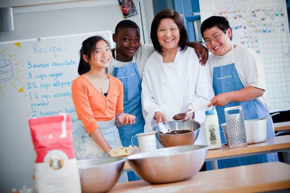 Culinary high school students standing in a kitchen and preparing to cook together. 
