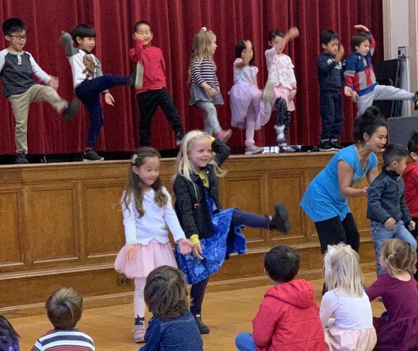 Corrine Nagata dancing with students in auditorium
