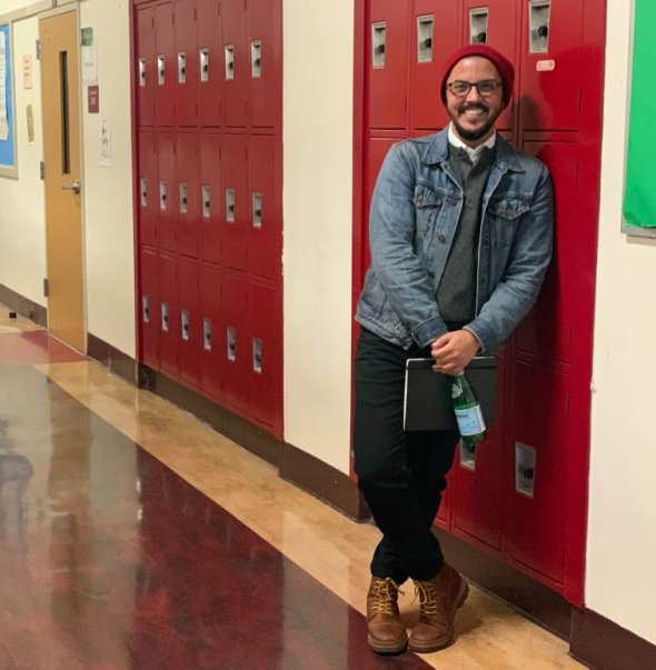 Staff member leaning on lockers in a hallway. 