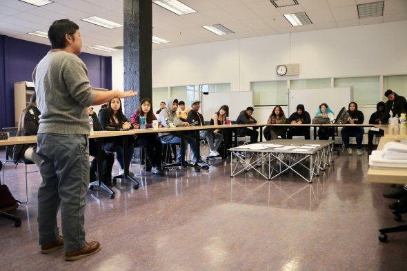  A group of high school students seated in a u-shaped seating arrangement. 