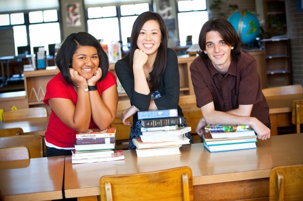 Three secondary students in the library with books