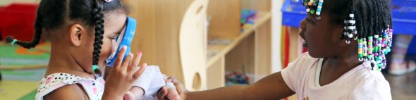 Two girls playing with doll and magnifying glass