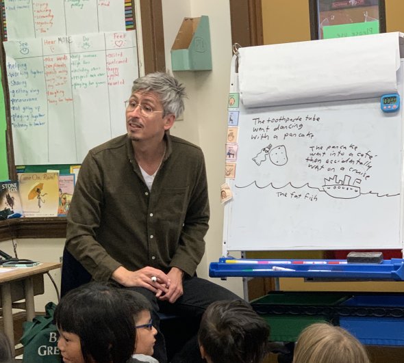 poetry teacher sitting by classroom easel