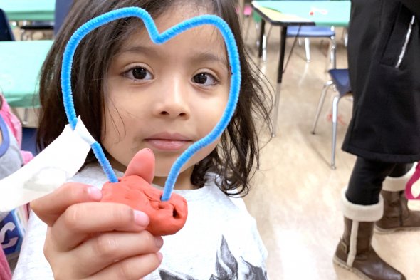 Girl holding art project and smiling at camera