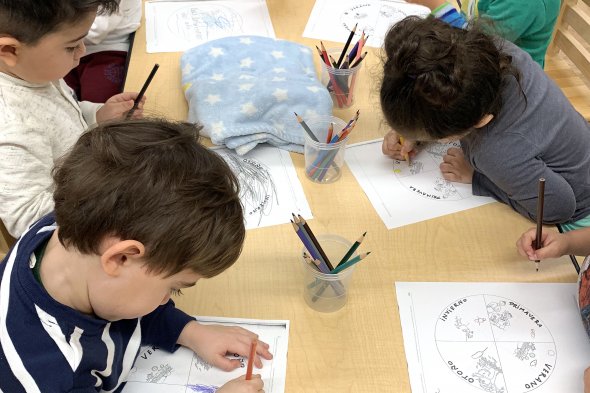 Three boys and girls sitting and writing at a table