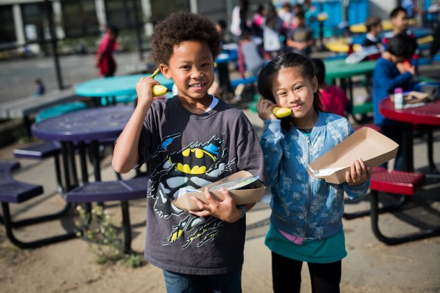 Two elementary school students using bananas as phones