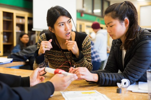 Science teacher working with physics student