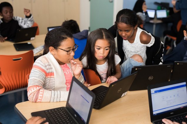 Three fifth-grade students collaborating on a chromebook