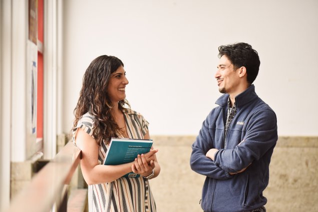 2 adults talking while one of them holds a book