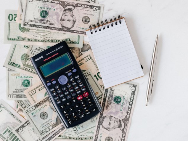 Calculator, blank notepad, and dollar bills of various denominations