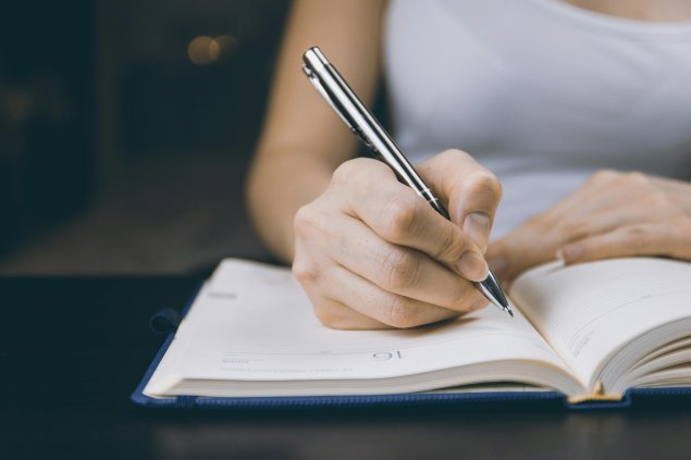 Hand holding pen writing in notebook