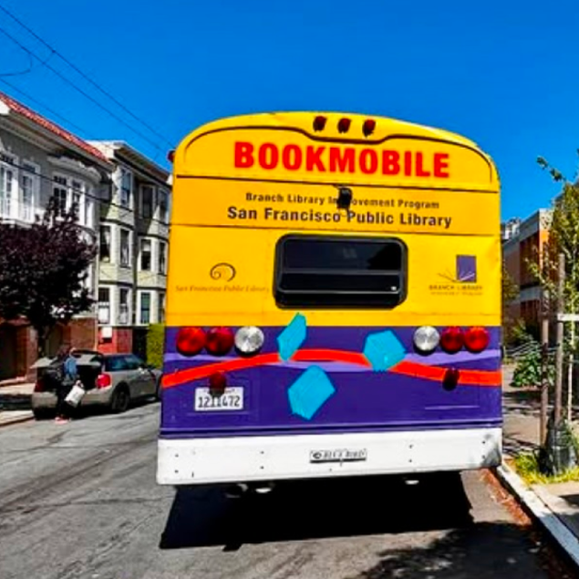 An image showing the back of a brightly colored San Francisco Public Library Bookmobile parked on a residential street in Cole Valley. The vehicle is painted yellow on the top half and purple on the bottom, with a red wavy line and blue book icons across the rear. The text "BOOKMOBILE" is printed in large red letters above "San Francisco Public Library".