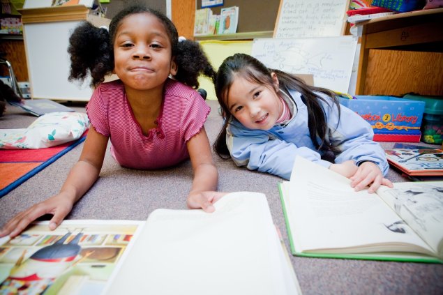 Girls smiling at camera while reading books