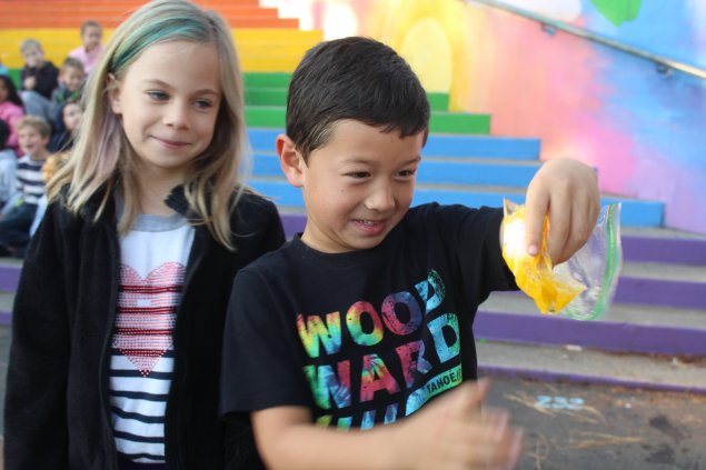 Boy holding bag with broken egg and girl watching over shoulder