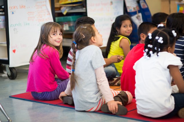 Elementary school students sitting on a rug