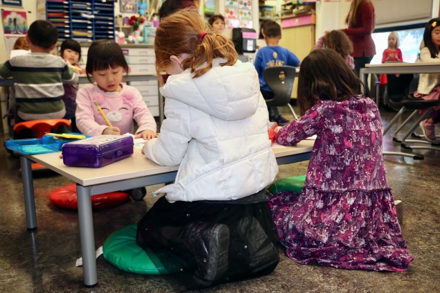 3 students sitting at a low table doing work