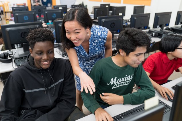 Teacher giving feedback to students on their project. 