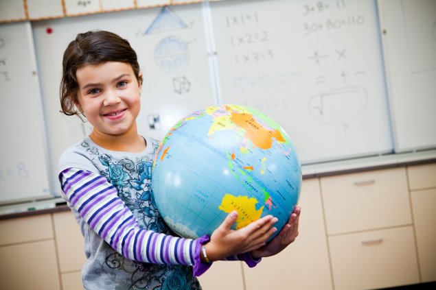 Girl holding globe in classroom