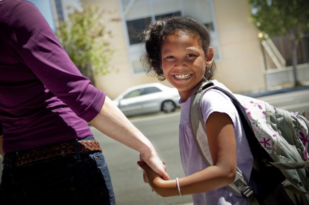 Student smiling, holding hands with family