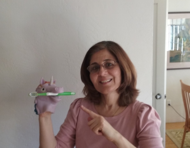 Fataneh Hamilton smiling and holding a dinosaur with a toothbrush in his mouth
