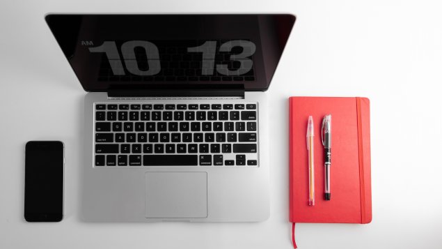 Desktop with phone, laptop, and notebook