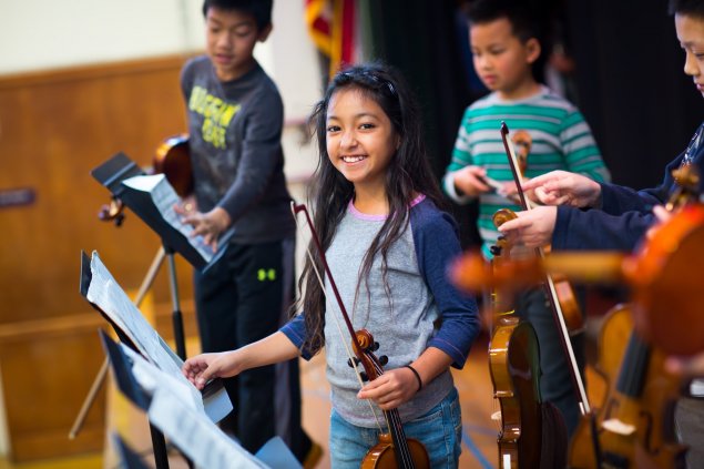 Children on stage, preparing for violin performance
